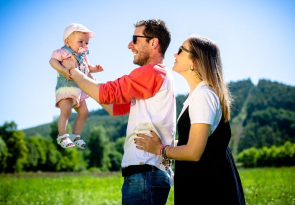 man in white and red polo shirt carrying girl in blue denim jeans during daytime