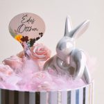 Charming Easter decoration with a ceramic bunny and pink roses in a striped box.